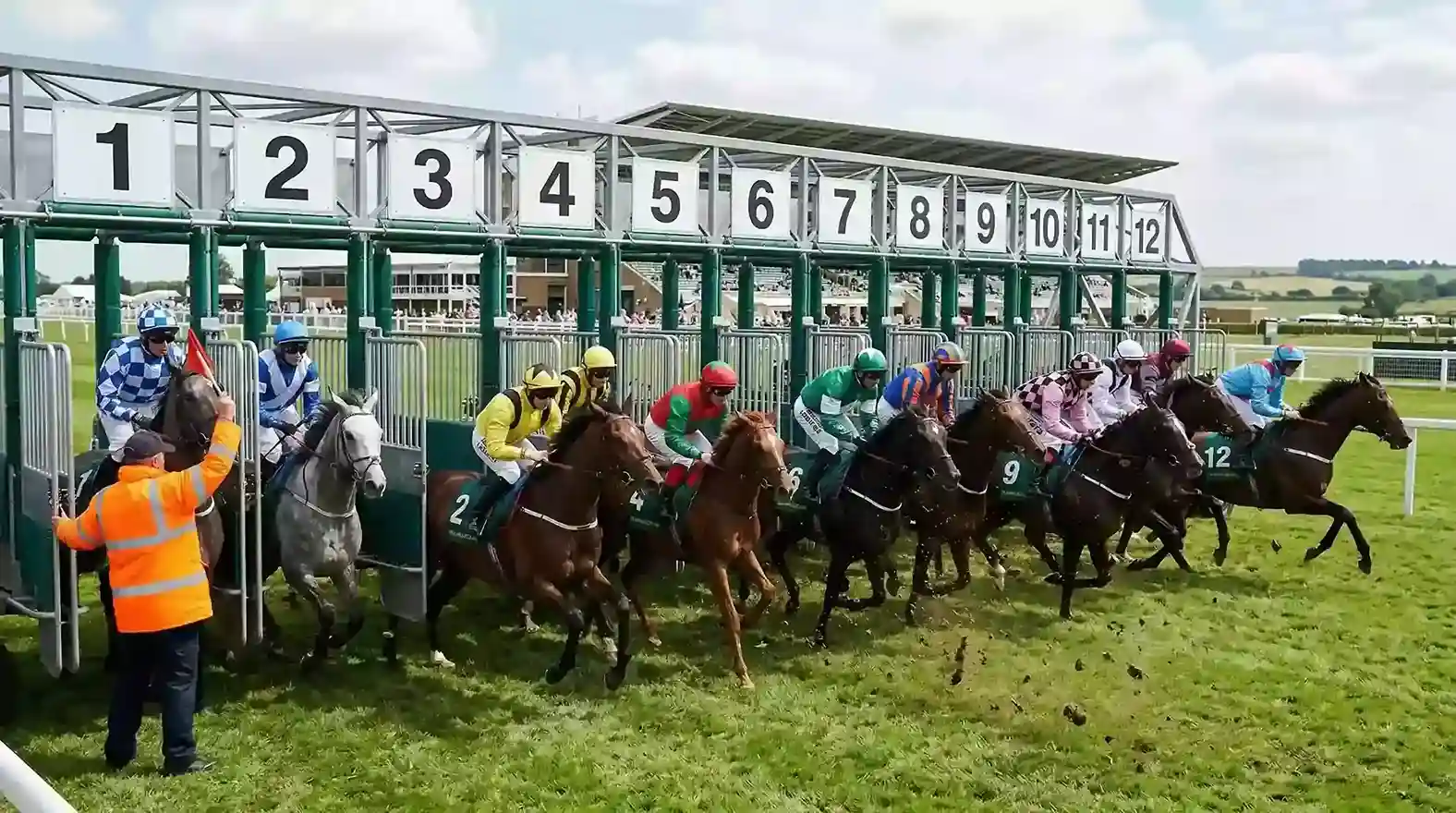 Starting stalls opening at a UK Flat race with a steward observing from the side